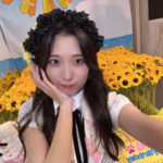 SKE48の石黒友月（いしぐろ ゆづき）さんが、生誕祭で向日葵（ひまわり）の生誕ディスプレイをバックに、黒い花冠を被って笑顔で写っている自撮り写真。
