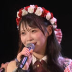 赤いバラと白いバラの花冠をつけ、マイクを持って笑顔でスピーチをするSKE48の浅井裕華。